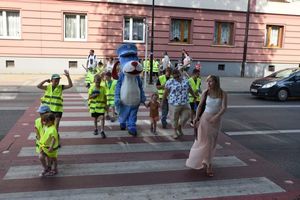 Maskotka Śląskiej Policji przechodzi wraz z dziećmi przez przejście dla pieszych