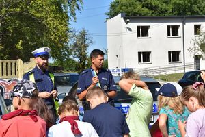 Policjanci podczas pogadanki z dziećmi prezentują sprzęt policyjny