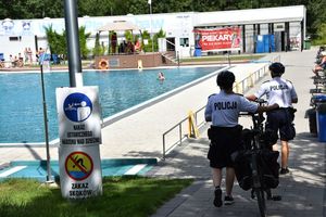 Policjanci prowadza rowery podczas kontroli basenu miejskiego