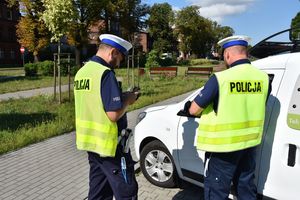 Policjanci stoją obok kontrolowanego pojazdu