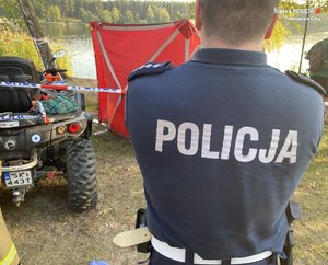 Policjant. W tle czterokołowiec, parawan oraz zbiornik wodny