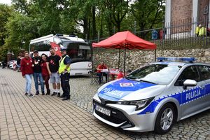 Policyjny radiowóz oraz ambulans. Policjant wraz z honorowymi dawcami krwi