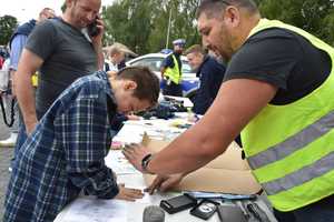 Na zdjęciu policjant pokazujący uczestnikom pikniku sposób zabezpieczania śladów.