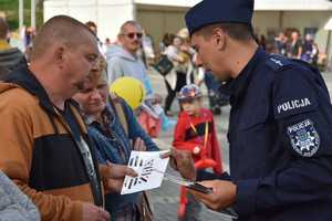 Na zdjęciu policjant rozdający ulotki uczestnikom wydarzenia.