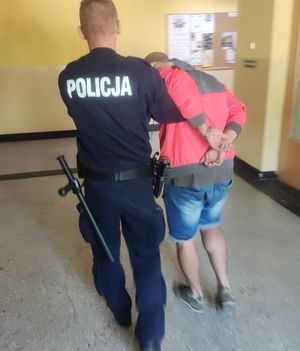 Na zdjęciu policjant nadzorujący osobę zatrzymaną.