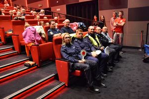 Policjanci oraz przedstawiciele samorządu oraz innych służb wraz z dziećmi w sali kina