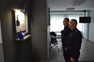 Policjanci stoją pod tablica pamiątkową