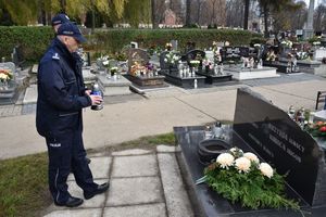 Policjant składa znicz przed grobem