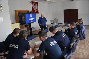 Policjanci siedzą przy stołach podczas szkolenia.