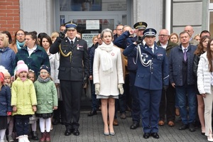 Osoby stoją przed budynkiem Urzędu Miasta. Mundurowi oddają honory