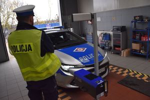 Policjant na tle radiowozu podczas kontroli ustawienia świateł