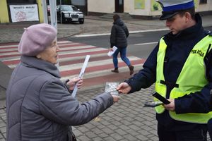 Policjantka wręczaja kobiecie odblask i ulotkę