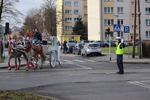 Zdjęcie przedstawia policjanta ruchu drogowego regulującego ruchem na skrzyżowaniu podczas przemarszu Orszaku Trzech Króli.