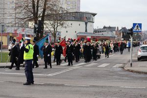 Zdjęcie przedstawia policjanta ruchu drogowego regulującego ruchem na skrzyżowaniu podczas przemarszu Orszaku Trzech Króli.