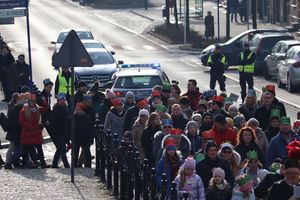 Zdjęcie przedstawia uczestników przemarszu Orszaku Trzech Króli oraz policjantów zabezpieczających imprezę.