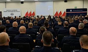 Zdjęcie przedstawia policjantów siedzących na sali