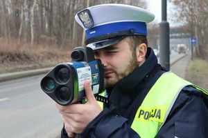 Zdjęcie przedstawia policjanta kontrolującego prędkość pojazdów