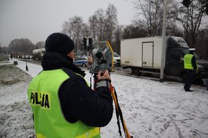 Zdjęcie przedstawia policjanta podczas wykonywania czynności na miejscu wypadku drogowego