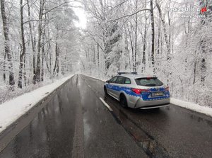 Oznakowany radiowóz na ośnieżonej drodze.