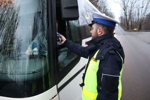 Zdjęcie przedstawia policjanta sprawdzającego trzeźwość u kierowcy autobusu