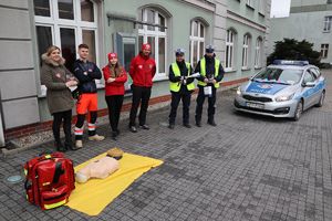 Zdjęcie przedstawia przedstawicieli Policji oraz Wodnego Ochotniczego Pogotowia Ratunkowego, którzy stoją przed budynkiem Urzędu Miasta