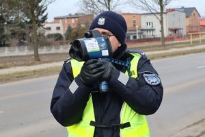 Zdjęcie przedstawia policjanta kontrolującego prędkość pojazdów