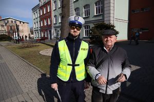 Zdjęcie przedstawia policjanta oraz mężczyznę na tle budynku