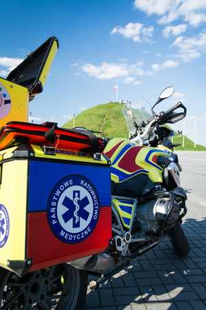 Zdjęcie przedstawia motoambulans na tle Kopca Wyzwolenia