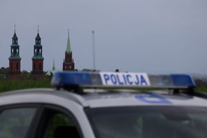 Zdjęcie przedstawia policyjny radiowóz na tle wież kościołów