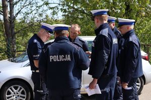 Zdjęcie przedstawia policjantów stojących przy samochodzie