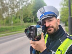 Zdjęcie przedstawia policjanta z radarem, który kontroluje prędkość