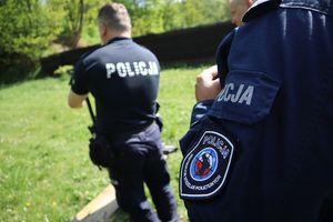 Zdjęcie przedstawia naszywkę instruktora strzelań policyjnych. w tle policjant