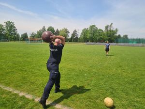 Zdjęcie przedstawia policjanta, który rzuca piłką podczas testów sprawnościowych