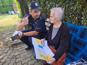 Zdjęcie przedstawia policjanta podczas rozmowy ze starszą osobą