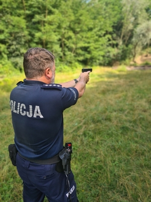 Zdjęcie przedstawia policjanta strzelającego w postawie stojącej