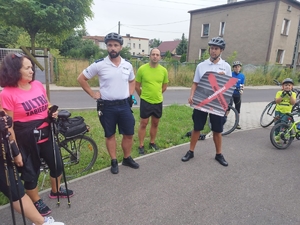 Zdjęcie przedstawia policjantów podczas pogadanki. Policjant trzyma w ręku plakat promujący kampanię społeczną &quot;Nie reagujesz-akceptujesz&quot;