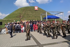 Zdjęcie przemarszu orkiestry wojskowej. W tle Uczestnicy uroczystości i Kopiec Wyzwolenia