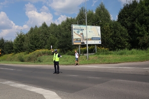 Zdjęcie przedstawia policjanta na skrzyżowaniu podczas regulacji ruchem