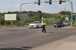 Zdjęcie przedstawia policjanta na skrzyżowaniu podczas regulacji ruchem