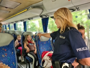 Zdjęcie przedstawia policjantkę podczas rozmowy z dziećmi w autokarze