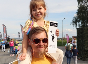 Zdjęcie przedstawia mężczyznę z dzieckiem na barkach