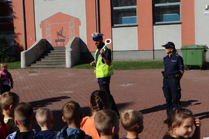 Zdjęcie przedstawia policjantów na placu szkolnym podczas spotkania z dziećmi