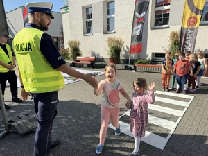 Zdjęcie policjanta oraz dzieci przechodzących przez utworzone przejście dla pieszych