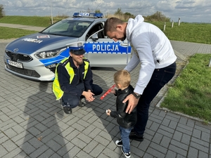 Zdjęcie przedstawia policjanta oraz dziecko przy radiowozie