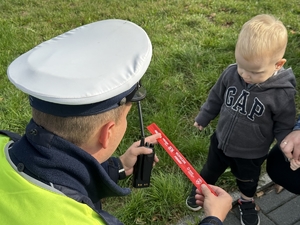 Zdjęcie przedstawia policjanta oraz dziecko, które ma odblaskową opaskę