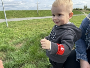 Zdjęcie przedstawia dziecko z odblaskową opaską na ręce