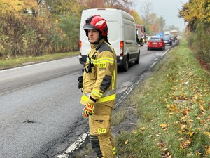 Zdjęcie przedstawia strażaka podczas kierowania ruchem w miejscy zdarzenia drogowego