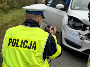 Zdjęcie przedstawia policjanta robiącego zdjęcia rozbitego samochodu