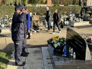 Zdjęcie przedstawia policjantów oddających honor przed grobem