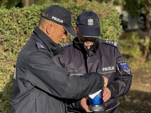 Zdjęcie przedstawia policjantów zapalających znicz